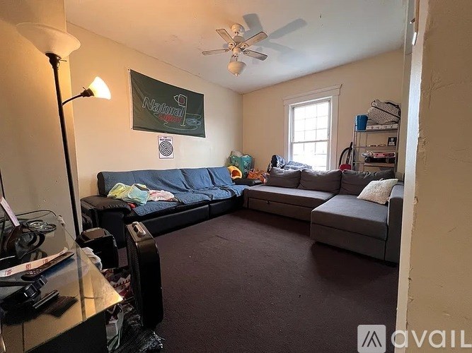 A living room with a couch, a chair, and a fan.