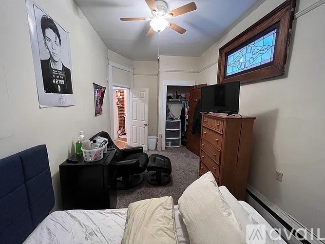 A bedroom with a bed, dresser, and a ceiling fan.
