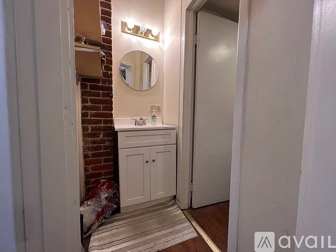 A bathroom with a white cabinet and a round mirror above it.