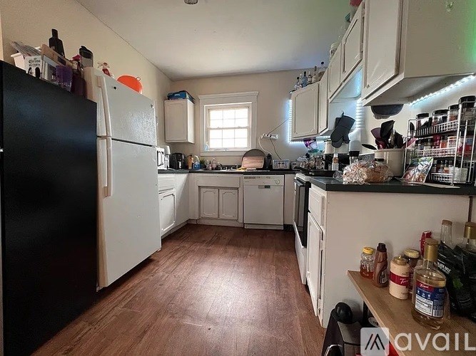 A kitchen with a black fridge and wooden floors.