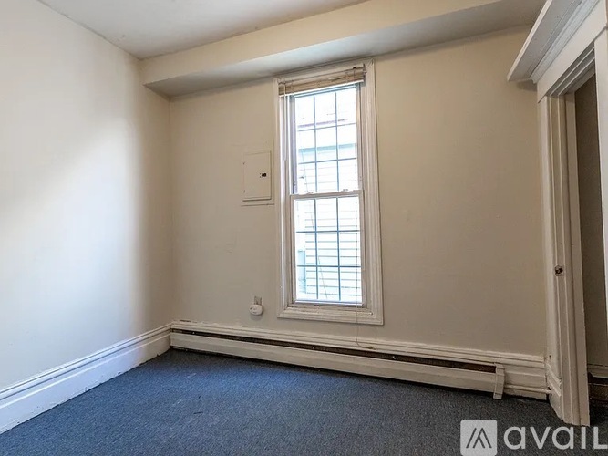 A room with a window and a carpeted floor.
