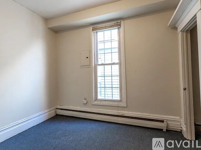 A room with a window and a carpeted floor.