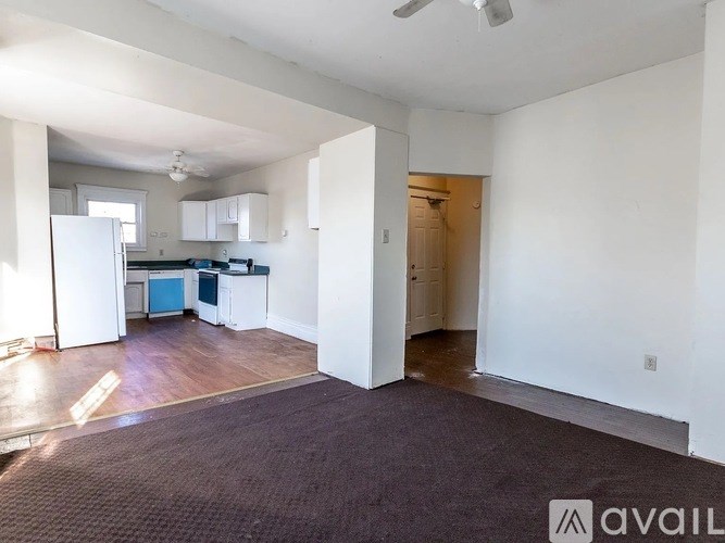A spacious living area with a kitchen in the background.