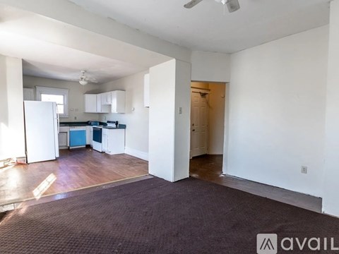 A spacious living area with a kitchen in the background.