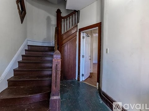 A wooden staircase with a railing and a mirror on the wall.