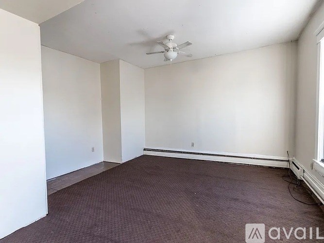 A room with a ceiling fan and carpeted floor.