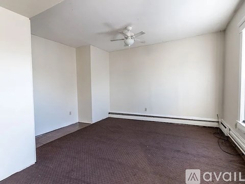 A room with a ceiling fan and carpeted floor.