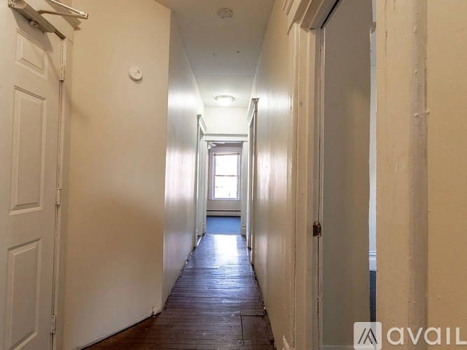 A long hallway with doors on both sides and a window in the distance.