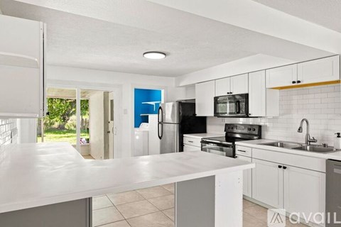 A modern kitchen with white countertops and stainless steel appliances.