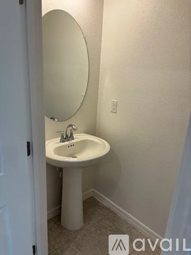 A white sink with a round mirror above it.