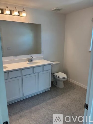 A bathroom with a toilet, sink, and mirror.