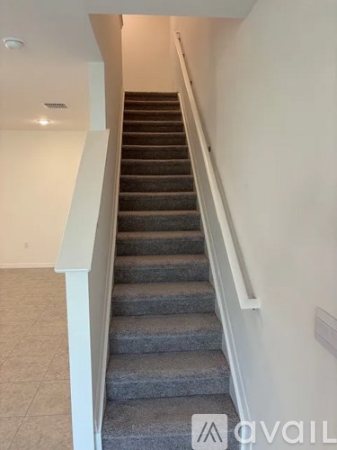 A staircase with a carpeted runner and white handrails.