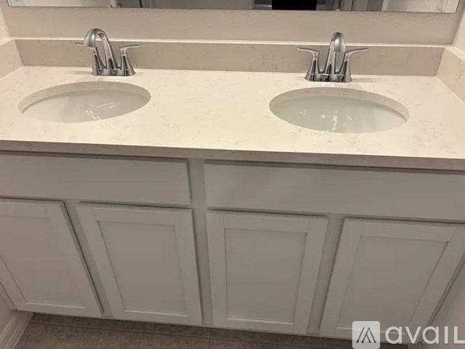 A bathroom with two sinks and white cabinets.