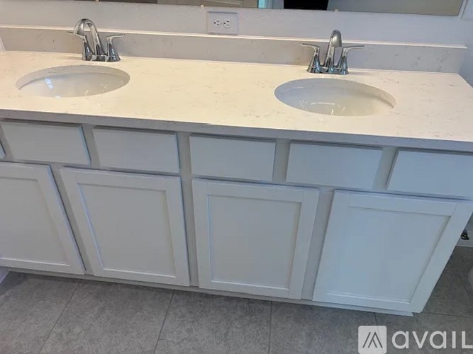 A bathroom vanity with two sinks and white cabinetry.