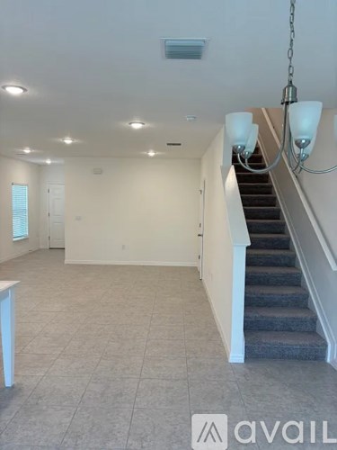 A spacious room with a staircase and a chandelier.