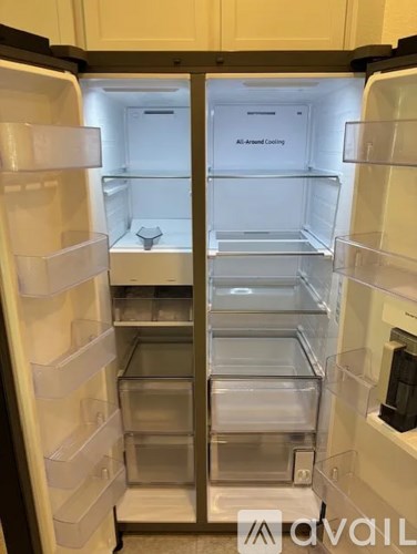 A white refrigerator with the door open showing all the shelves empty.