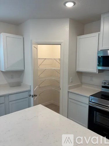 A kitchen with white cabinets and a marble countertop.