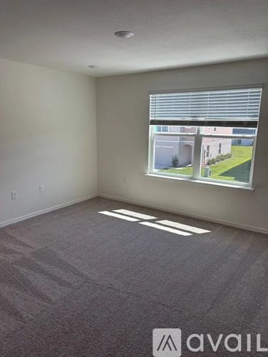 A room with a carpeted floor and a window showing a view of a building.
