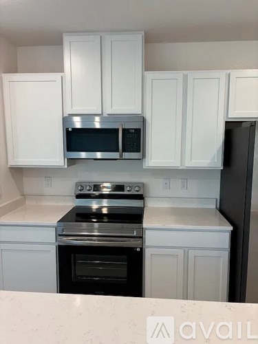 A kitchen with white cabinets and a black refrigerator.