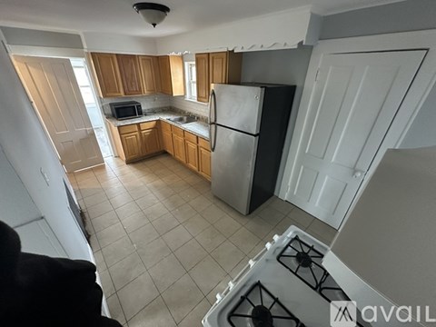 A kitchen with wooden cabinets and a stainless steel refrigerator.