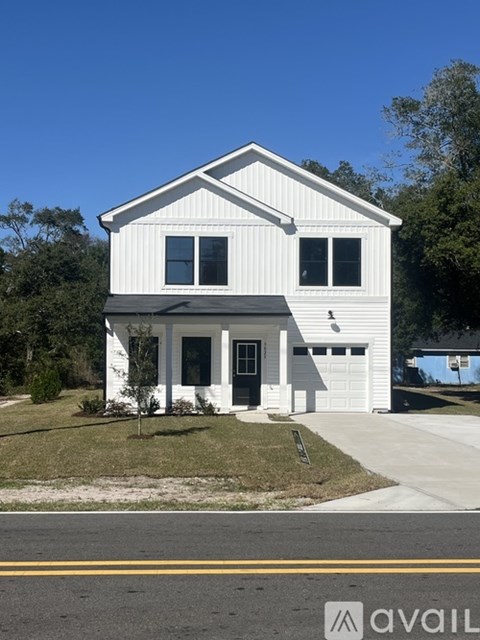 A white house with a black roof and a garage door is for sale.