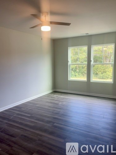 A room with a ceiling fan and a window overlooking greenery.