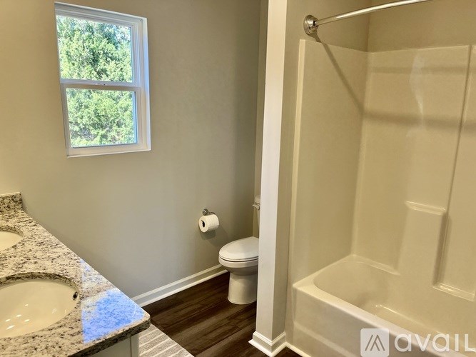 A bathroom with a window, sink, toilet, and bathtub.
