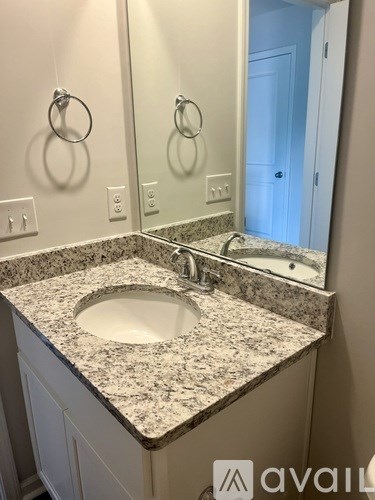 A bathroom sink with a granite countertop and a mirror above it.