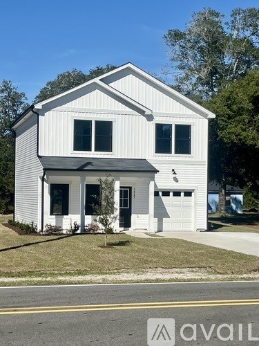 A white house with a black roof and a garage door.