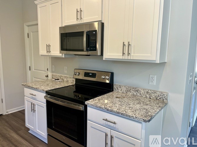 A kitchen with white cabinets and a granite countertop.