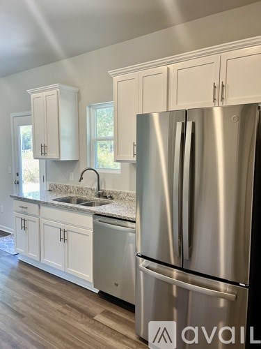 A modern kitchen with a stainless steel refrigerator and white cabinets.