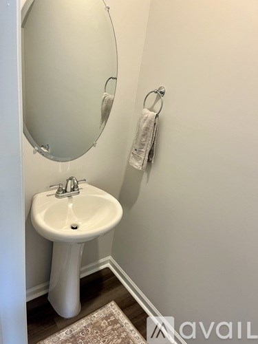 A white pedestal sink with a round mirror above it.