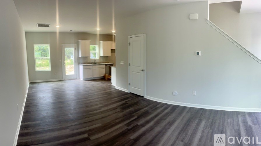 A spacious room with wooden flooring and white walls.