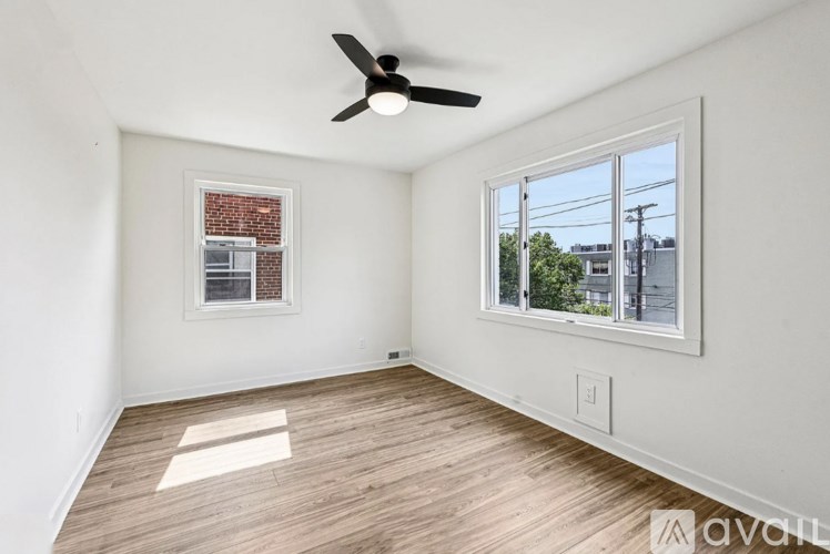 A room with a ceiling fan and a window overlooking a street.