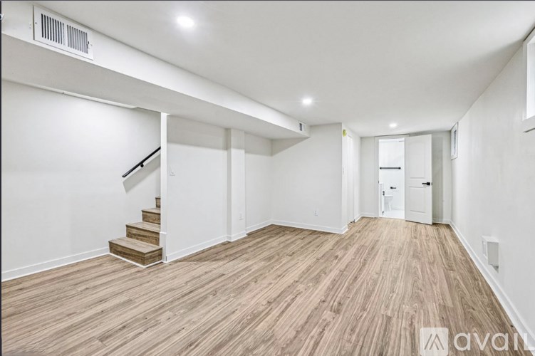 A spacious room with wooden flooring and a staircase leading to another level.