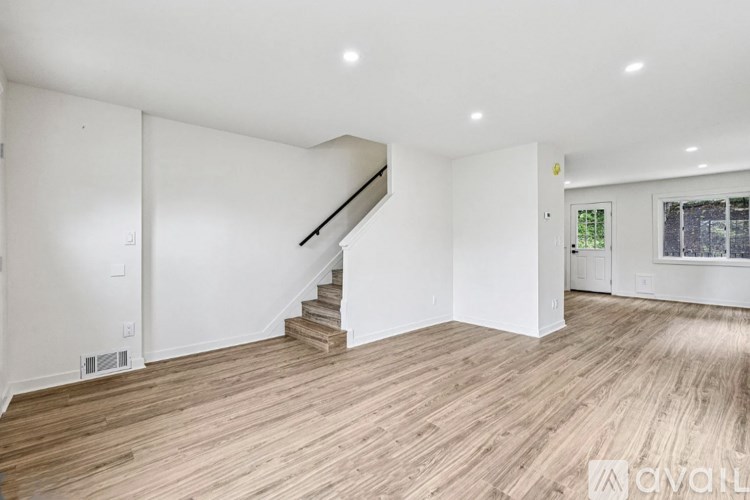 A spacious room with wooden flooring and a staircase leading to another level.