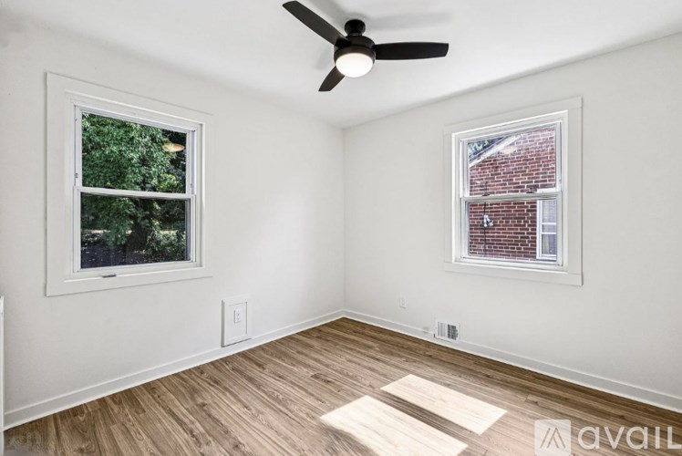 A room with a ceiling fan and two windows.