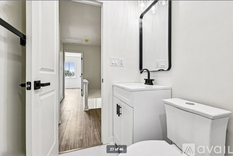 A white bathroom with a toilet, sink, and mirror.