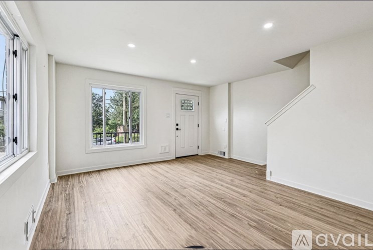 A spacious room with wooden flooring and white walls.