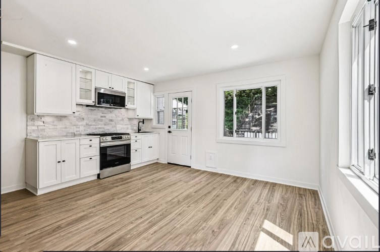 A kitchen with white cabinets and a wooden floor.
