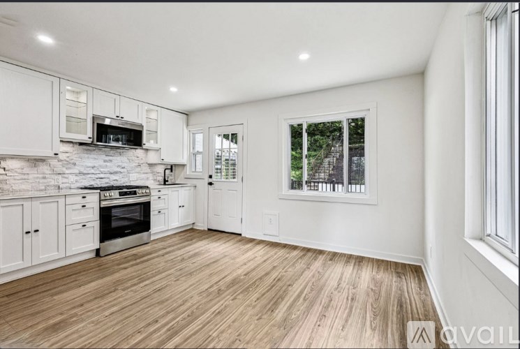 A kitchen with white cabinets and a wooden floor.