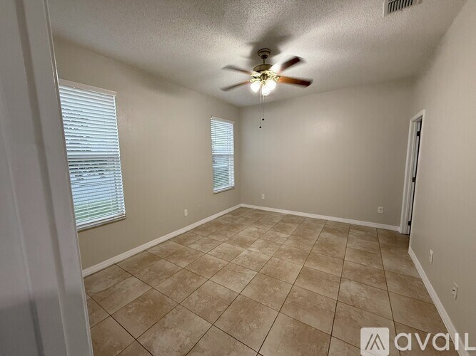 A room with a ceiling fan and tiled flooring.