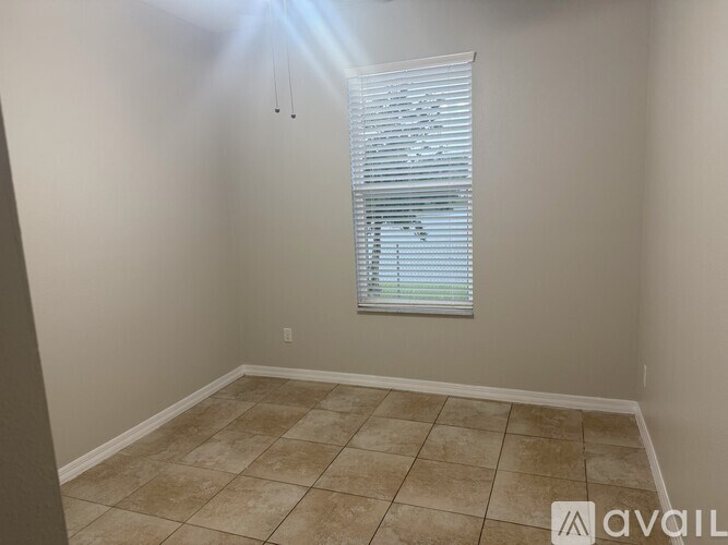 A room with a window covered by white blinds.