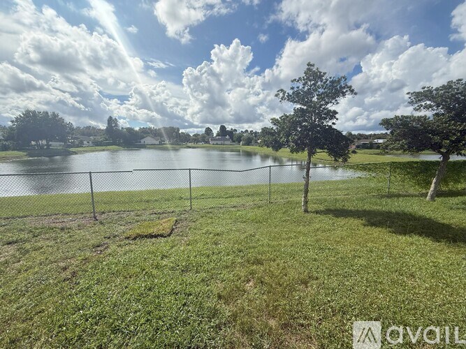A grassy area with a lake and trees in the distance.