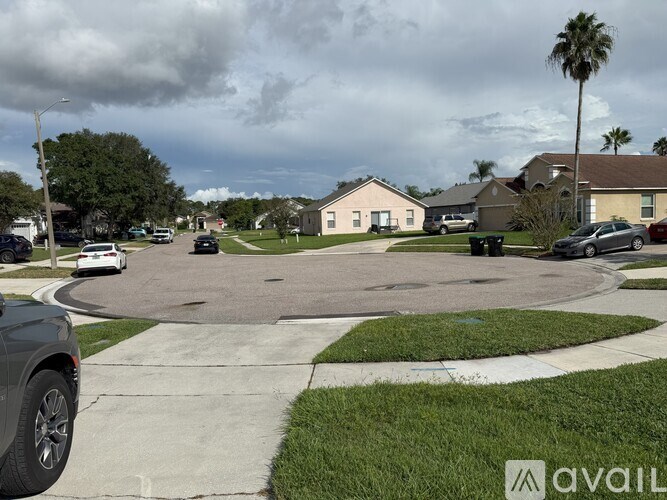 A suburban street with cars parked on the side and houses in the background.