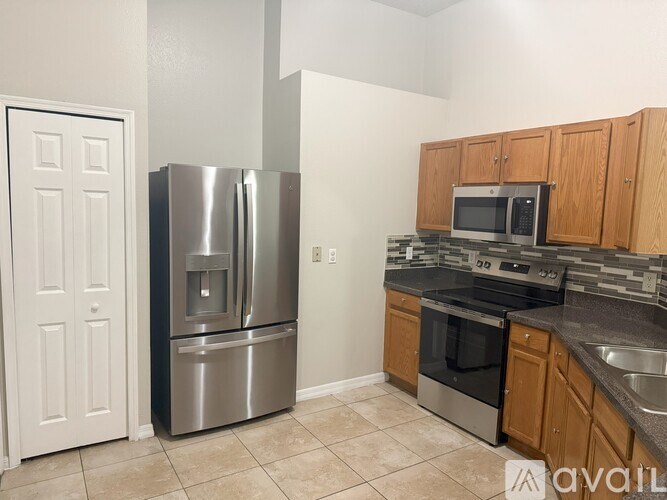 A kitchen with a refrigerator, oven, microwave, and sink.
