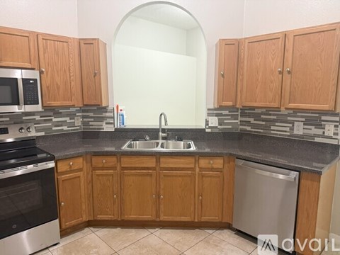 A kitchen with wooden cabinets and a stone backsplash.