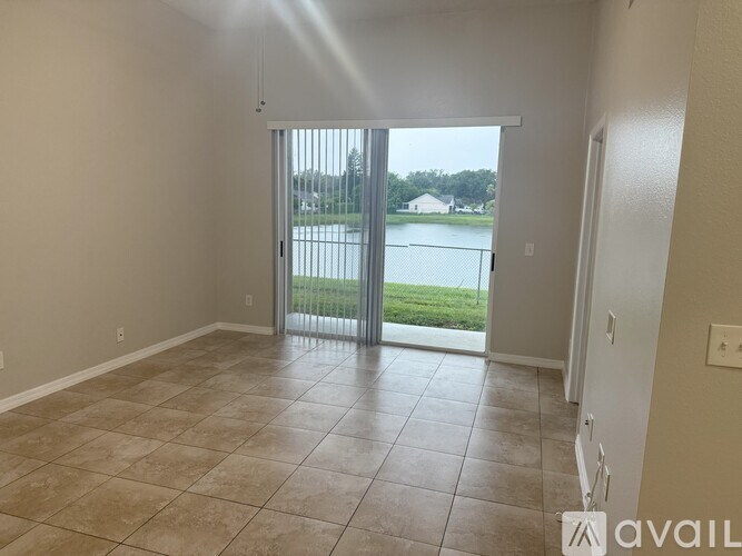 A room with tiled flooring and a sliding glass door leading to a balcony.