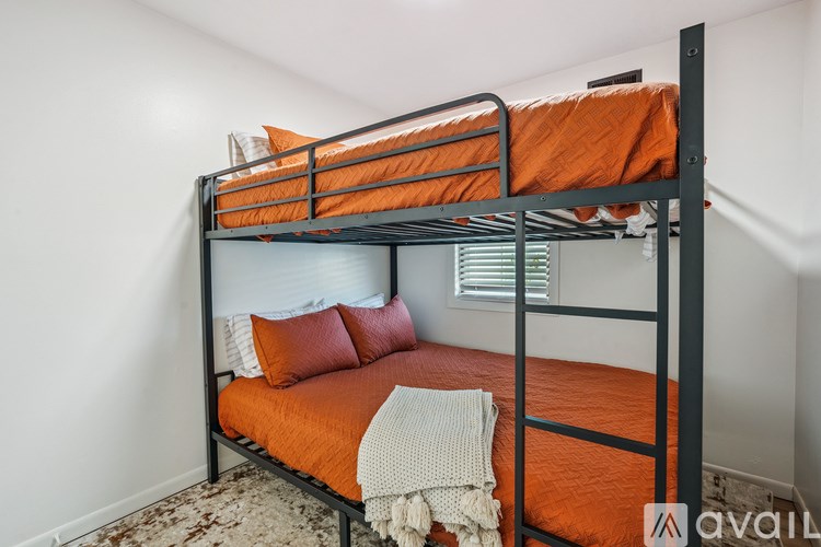 A bunk bed with an orange sheet and pillows.