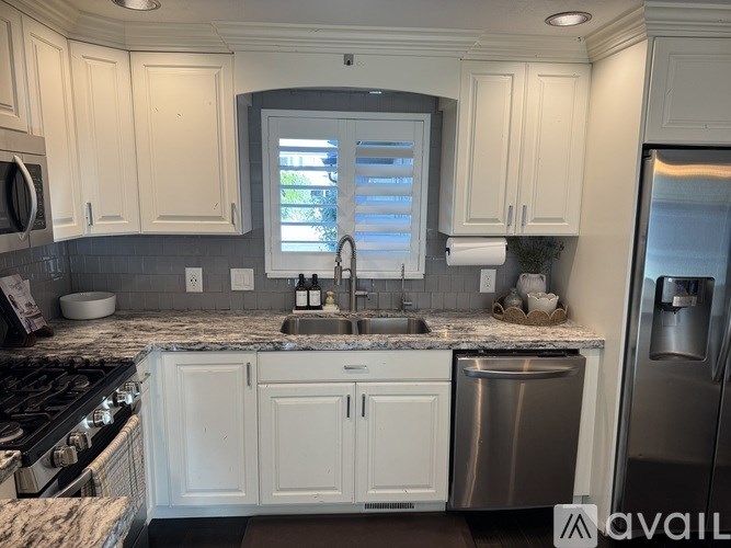 A kitchen with white cabinets and a granite countertop.